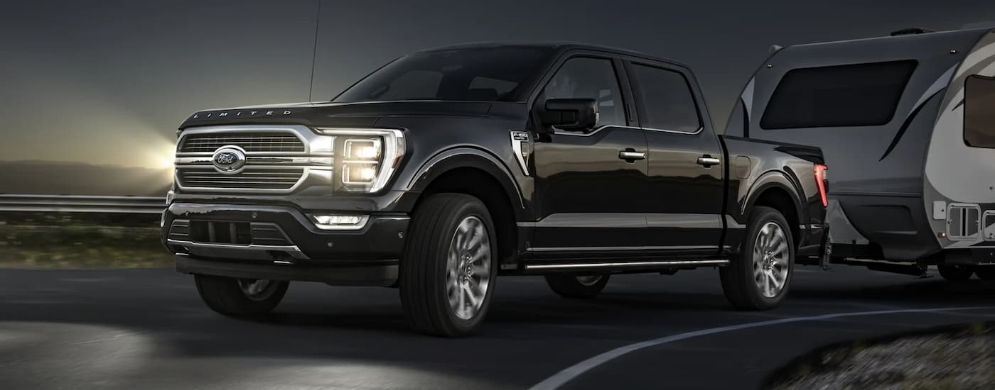 Black 2022 Ford F-150 towing a camper at night