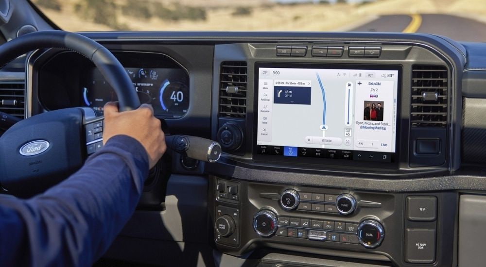 A driver using the navigation screen in a 2025 Ford F-250 for sale.