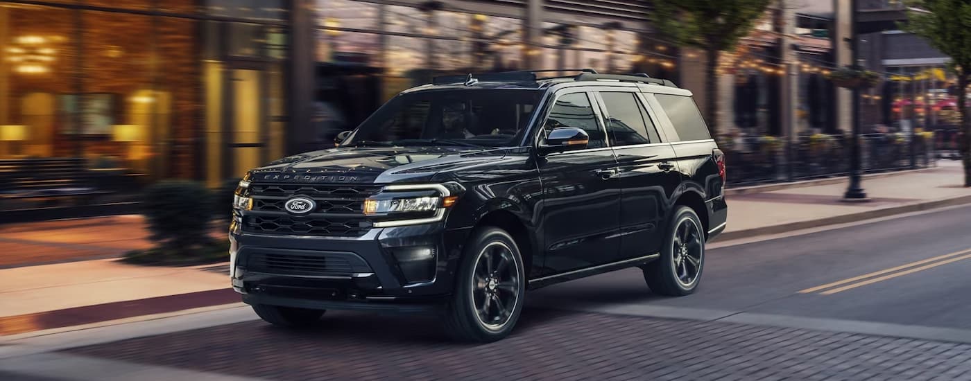 Black 2024 Ford Expedition driving on a road to a used car dealer