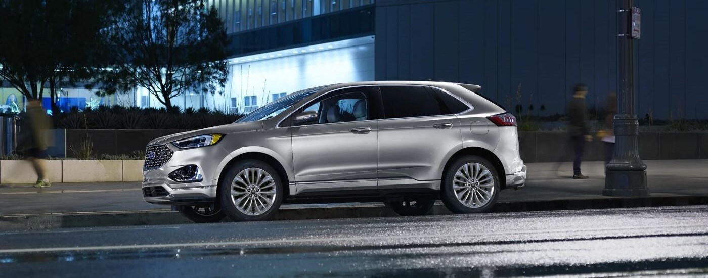 Side view of a silver 2023 Ford Edge, a used Ford for sale near Toledo, parked on a city street at night.