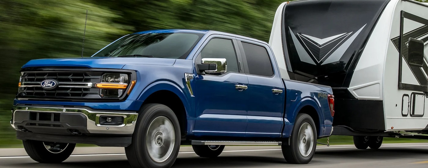A blue 2024 Ford F-150 towing a white RV.
