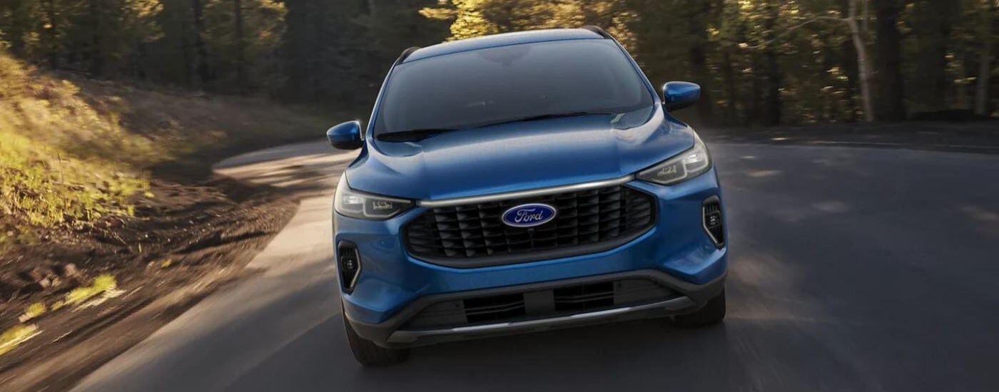 Blue 2023 Ford Escape driving down a rural road