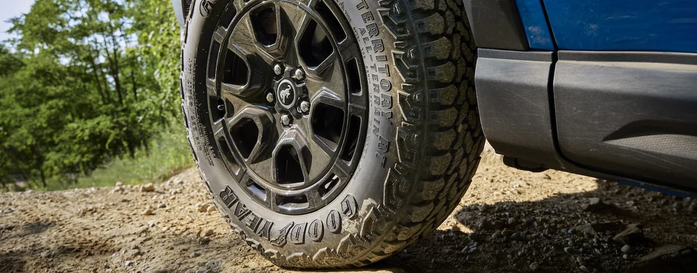Close up of the rim and tire on a muddy blue 2025 Ford Bronco Sport