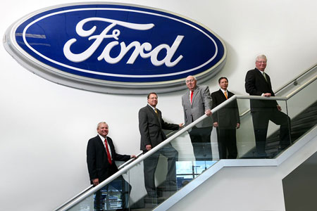 Business people standing on stairs under a Ford sign