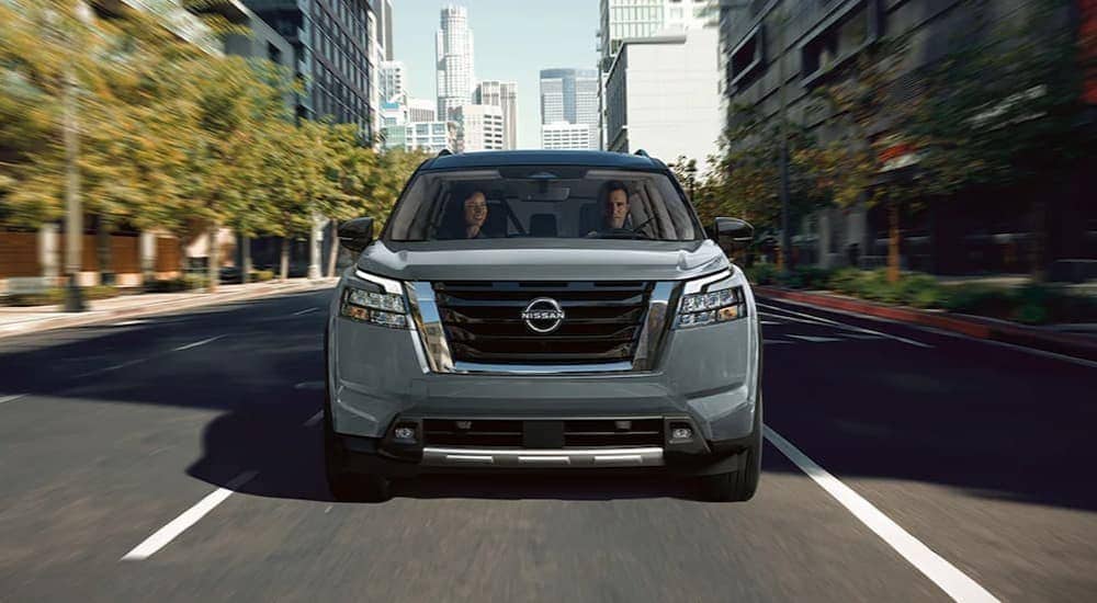 A gray 2025 Nissan Pathfinder for sale driving in a city.