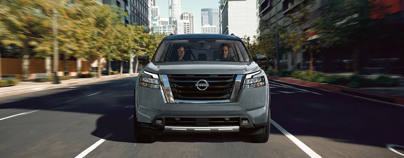 A silver 2025 Nissan Pathfinder Platinum is shown driving on a city street.
