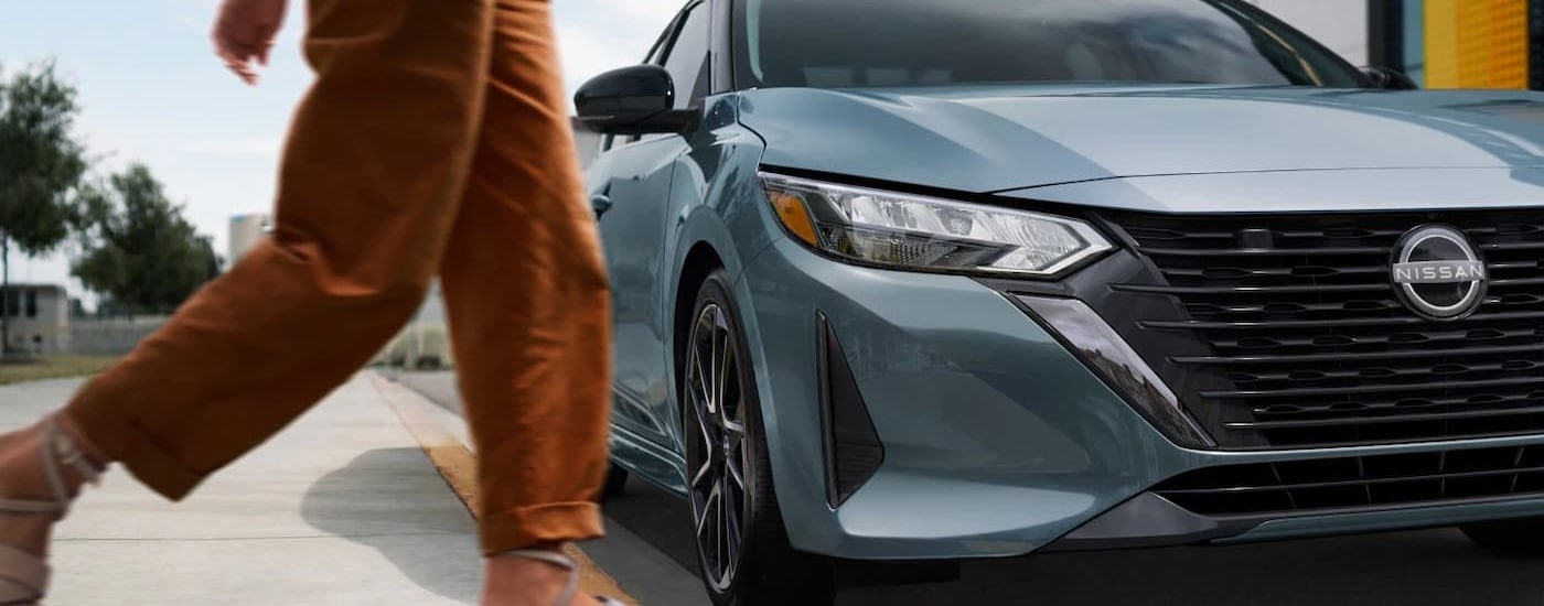 A person walking near a light blue 2025 Nissan Sentra.