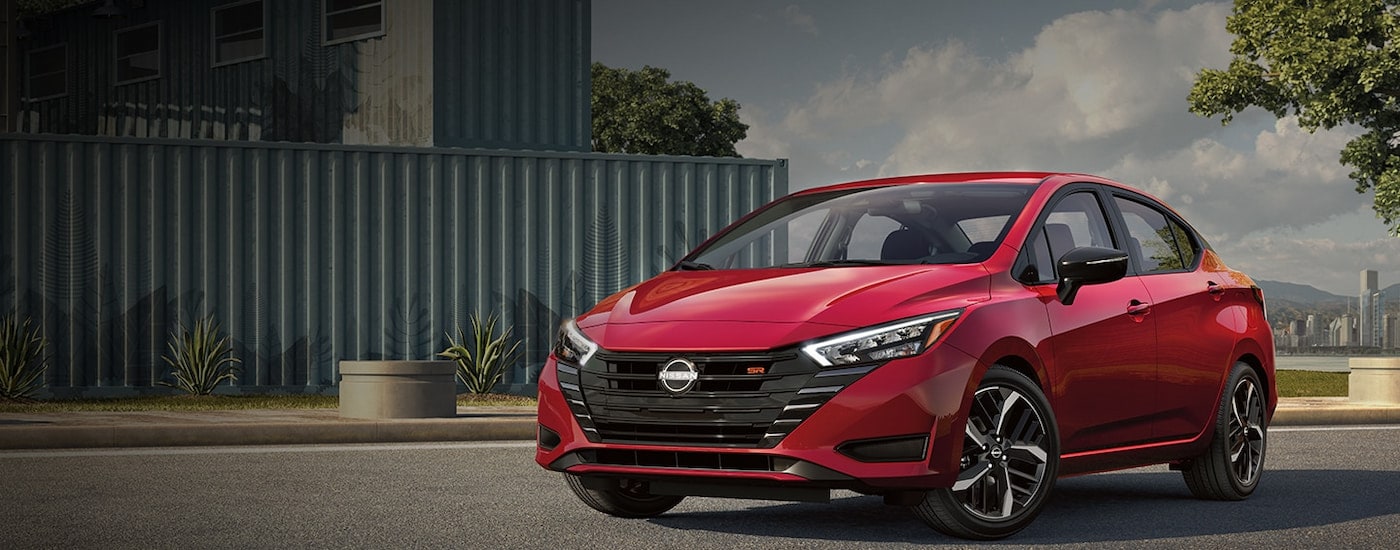 A red 2024 Nissan Versa parked outside a Nissan dealer near Piqua.