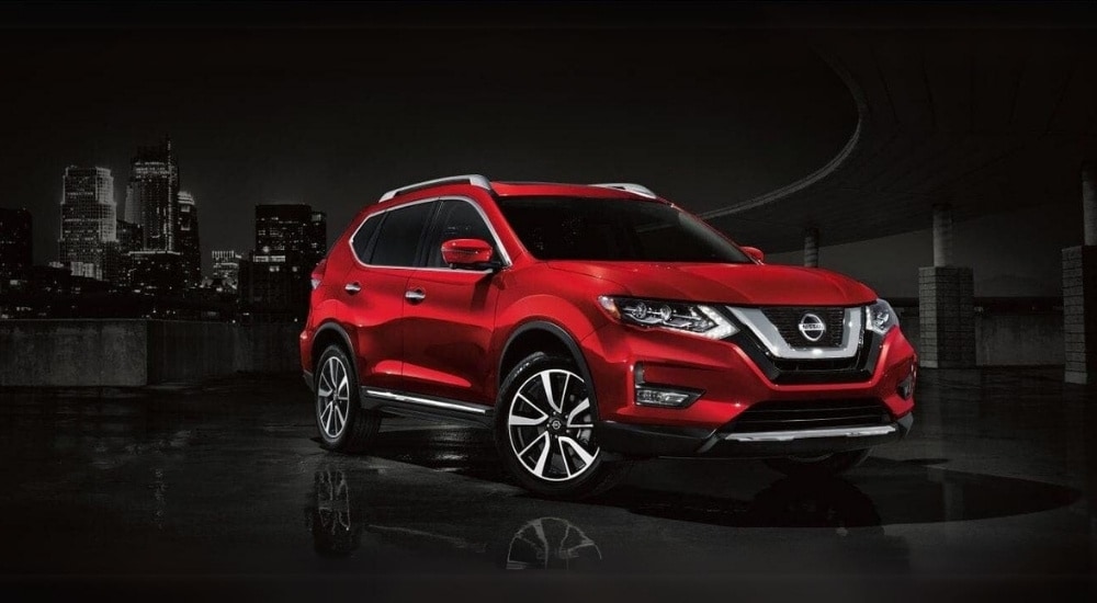 A red 2017 Nissan Rogue is shown near a city after visiting used car dealers.