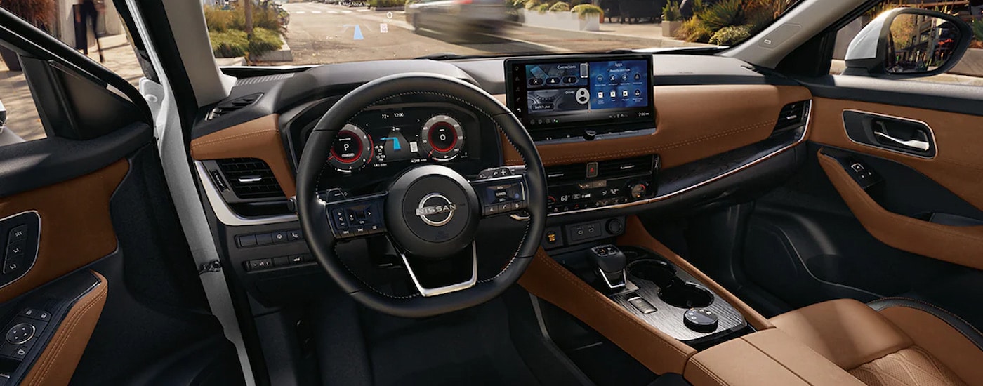 Brown leather upholstery and multiple infotainment screens in the cabin of a 2024 Nissan Rogue for sale.