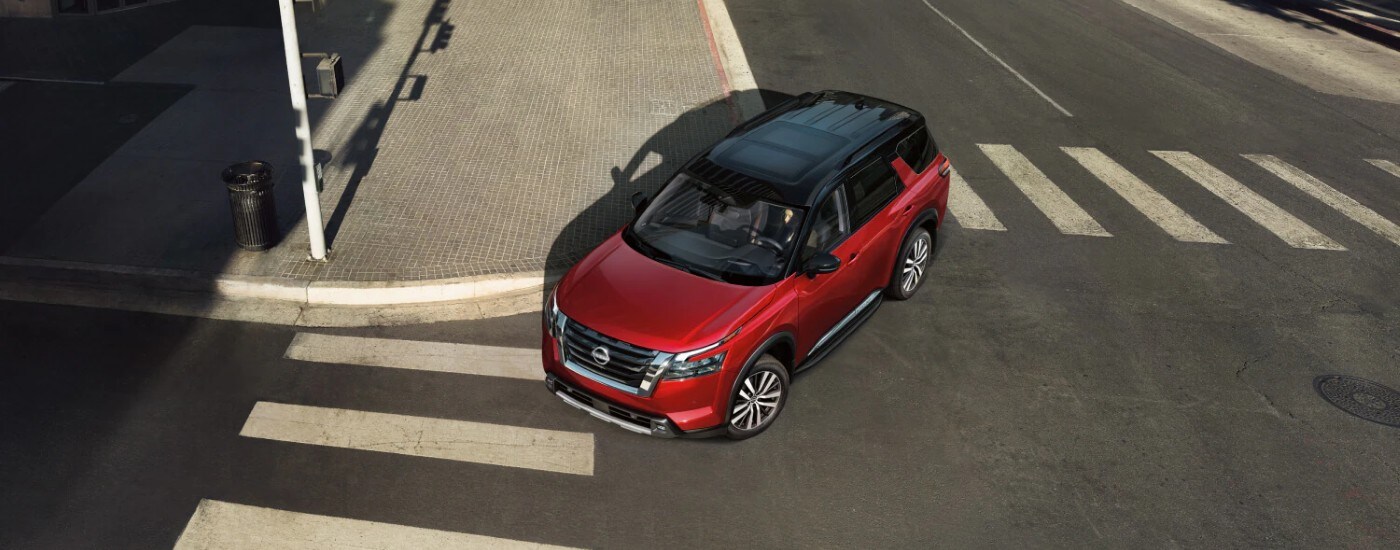 Red 2025 Nissan Pathfinder for sale on a test drive.