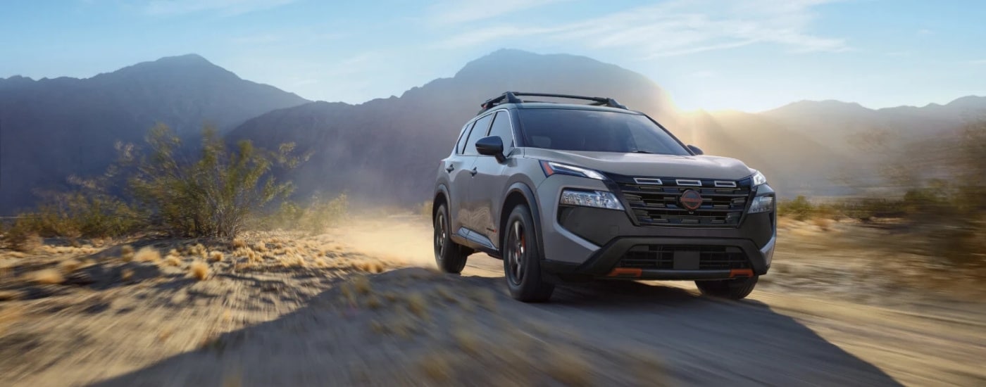 A grey 2025 Nissan Rogue Rock Creek driving on a dusty trail.