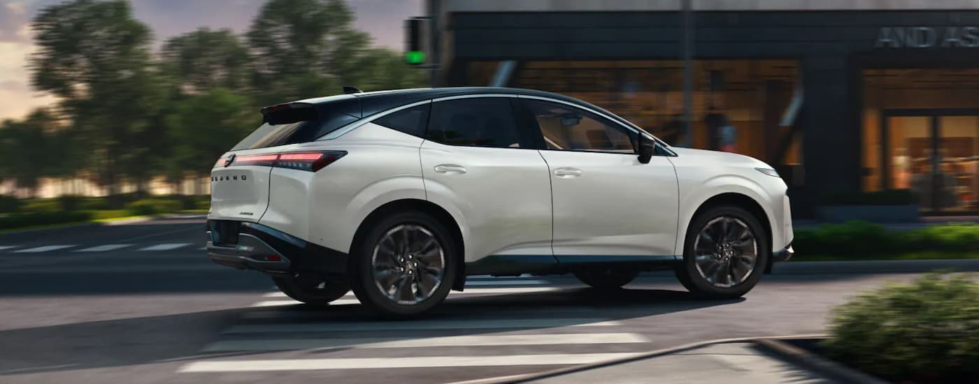 Side view of a white 2025 Nissan Murano Platinum driving on a city street