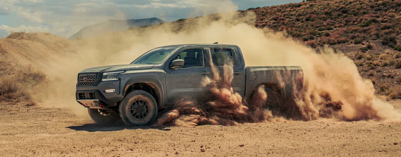 A grey 2022 Nissan Frontier driving off-road in a desert from a Nissan dealer near Celina.
