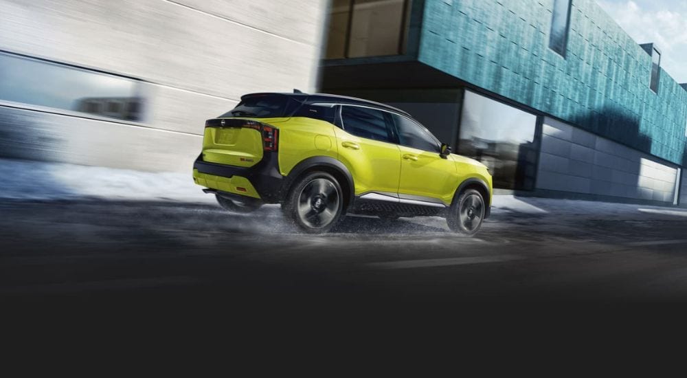 A green 2025 Nissan Kicks is shown driving to one of the most popular Nissan dealers near you.