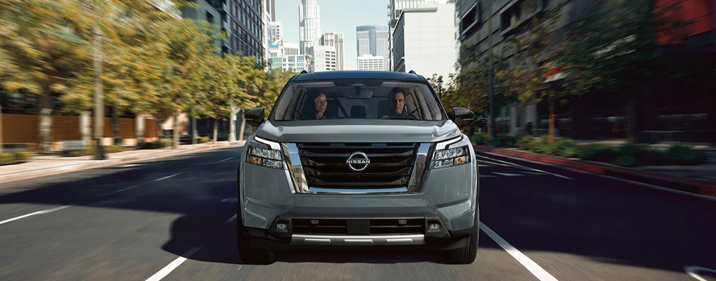 A gray 2025 Nissan Pathfinder Platinum is shown driving in a city.