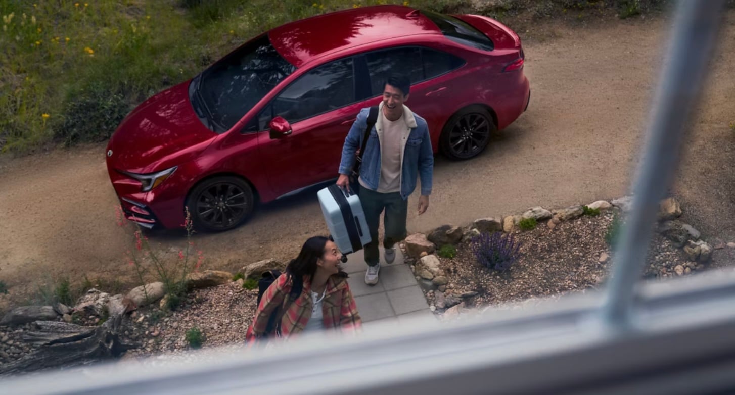  The New Corolla shown from a top down view through a window with a man bringing a suitcase into his home.