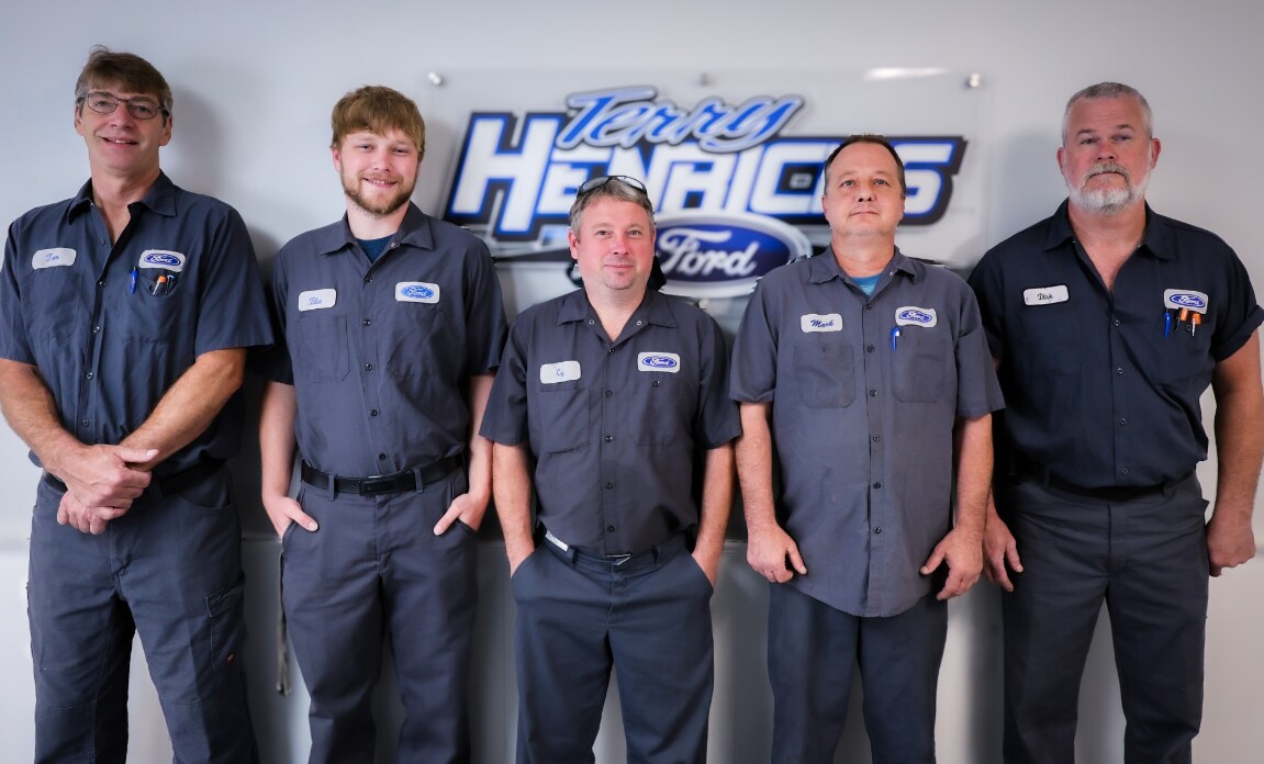 Five Senior Master Technicians stand in front of a sign reading