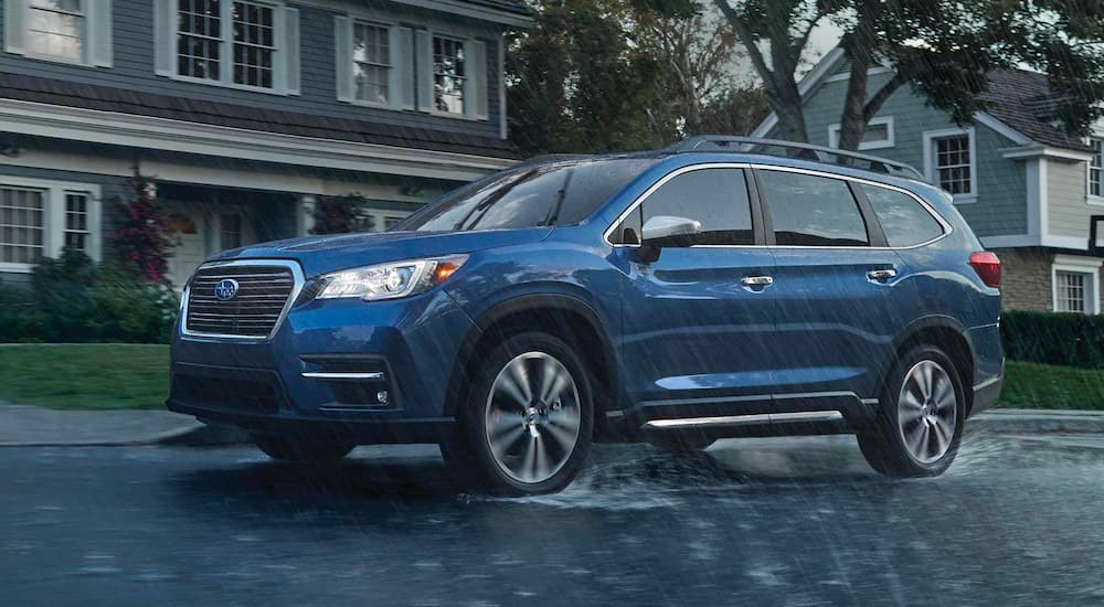A blue 2021 Subaru Ascent is shown from the side driving in the rain after leaving a Subaru dealership.