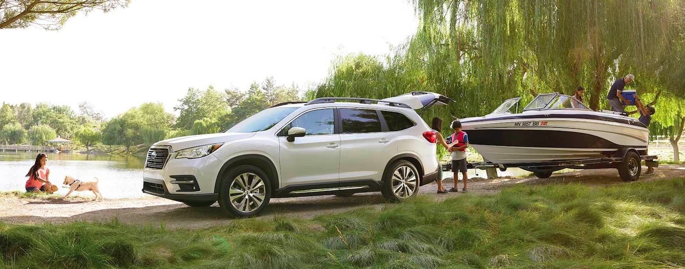 NJ Subaru Ascent Dealer - 2022 Subaru Ascent Limited - Boat (1).jpg A white 2022 Subaru Ascent Limited is shown from the side attached to a boat near a lake and family.