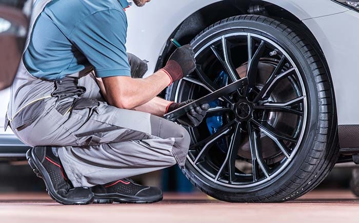 Professional inspecting tires and wheels during a vehicle maintenance check up.