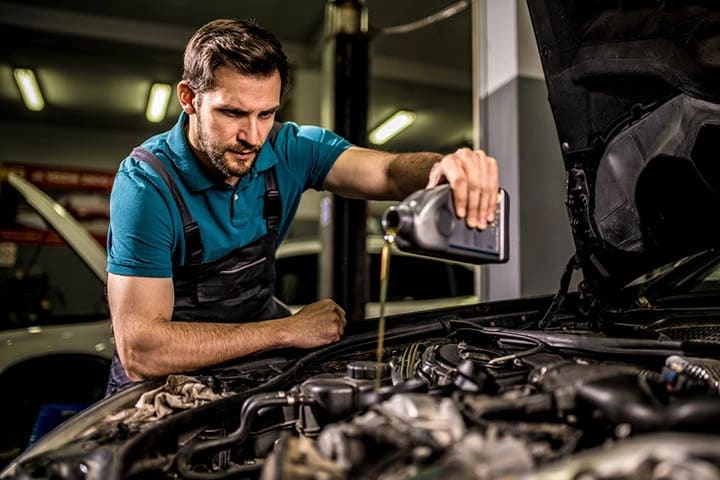 An auto mechanic performs an oil change on the car to improve the vehicle’s fuel efficiency at the car workshop