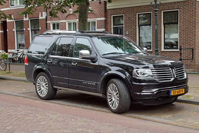 A Black Lincoln Navigator parked by the side of the road.