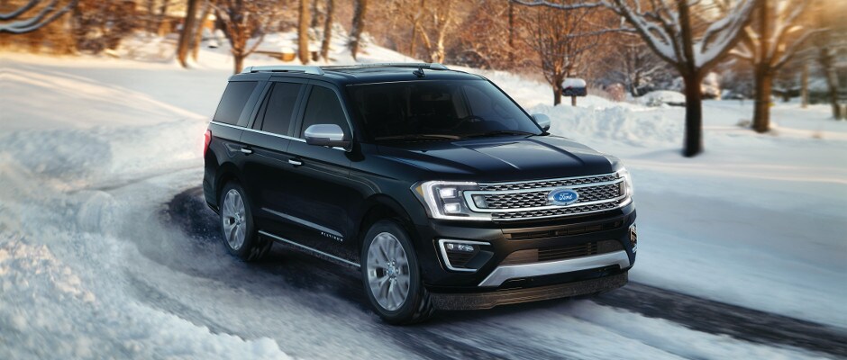 A black Ford Expedition driving through the snow