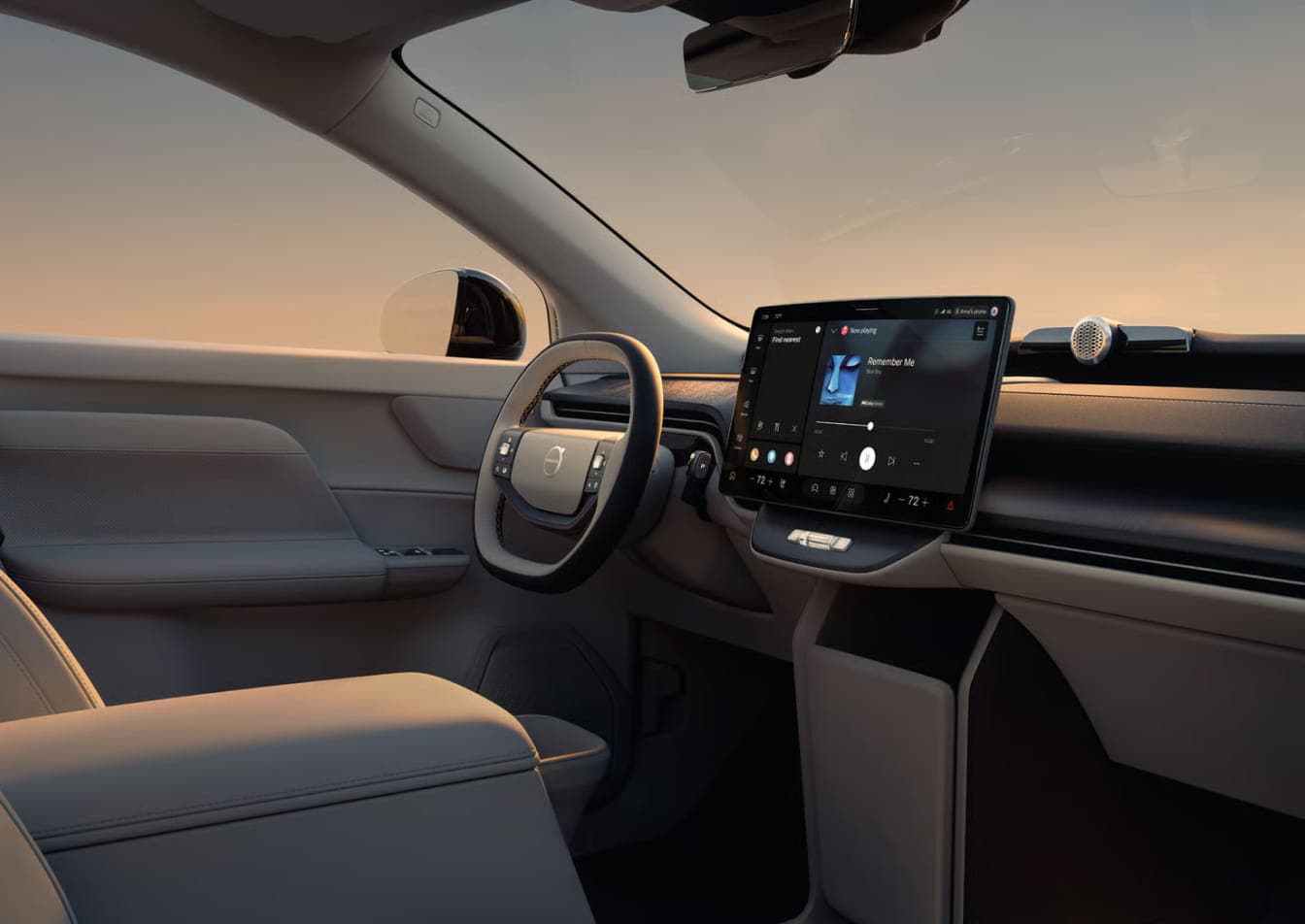 2026 Volvo EX60 interior with a sleek design, featuring a large touchscreen display on the dashboard, a steering wheel, and a serene sunset in the background.