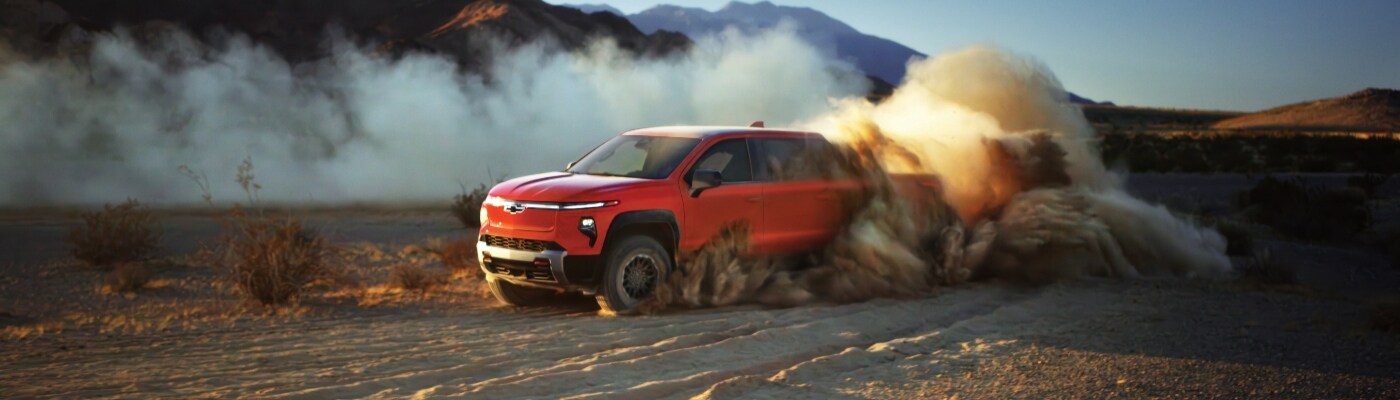 Chevy Silverado EV kicking up dirt driving down an unpaved road