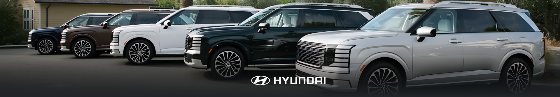 Several Hyundai Palisades lined up in a tree-lined parking lot.