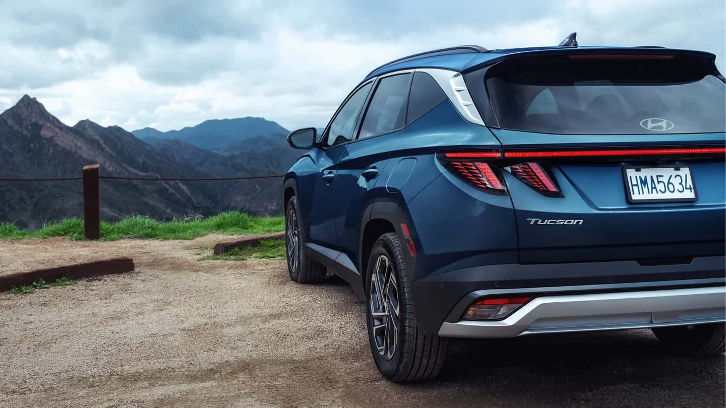 A rear view of a blue Hyundai Tucson, parked overlooking a mountain range