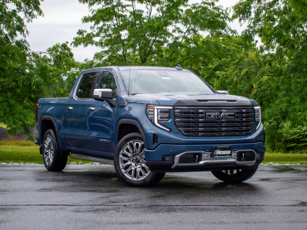 Blue GMC Sierra 1500 Denali Ultimate viewed from the front on a tree-lined road