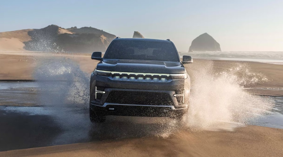 2026 Jeep Grand Wagoneer luxury SUV driving through ocean surf on the beach, highlighting Quadra-Drive II 4x4 capability near East Brunswick, NJ.
