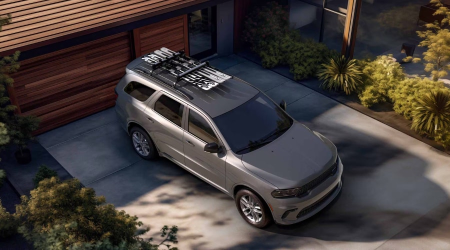 High-angle view of a silver 2026 Dodge Durango AWD with a ski roof rack parked in a residential driveway in East Brunswick NJ, showcasing all-weather versatility for autumn and winter driving in Middlesex County.