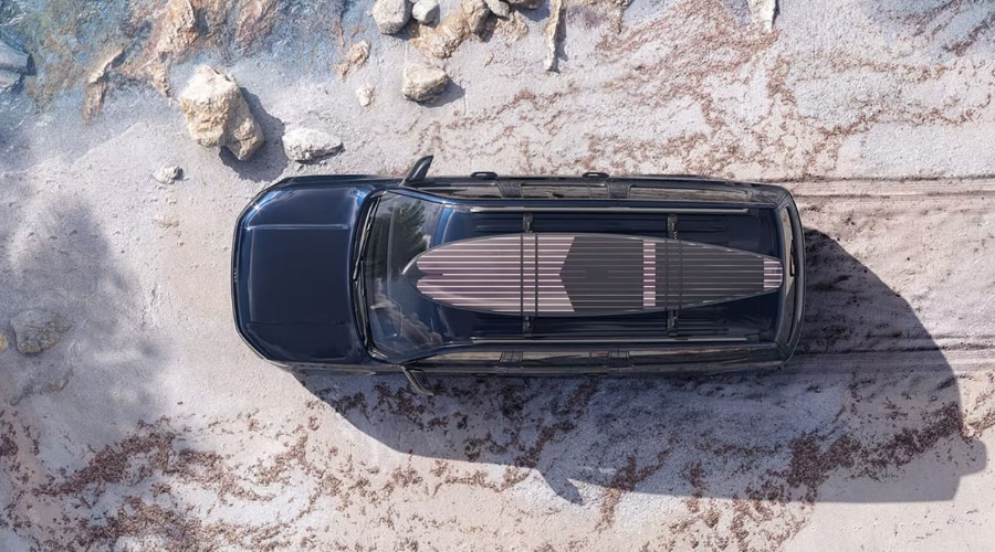 Aerial top-down view of a dark blue 2026 Jeep Grand Wagoneer parked on a sandy beach with surfboards on the roof rack, available at Route 18 Autos in East Brunswick, NJ.