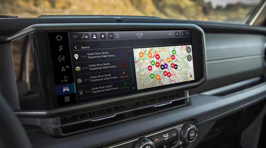 Close-up view of the central Uconnect touchscreen display inside a 2026 Jeep Wrangler showing trail navigation maps and cabin climate controls, highlighting advanced technology for autumn driving at Route 18 Autos in East Brunswick, NJ.