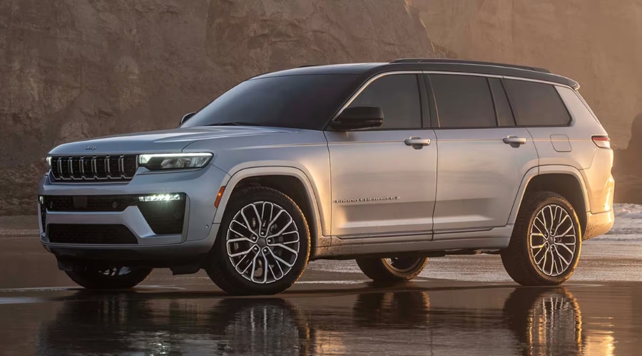 Front profile of a 2026 Jeep Grand Cherokee driving through East Brunswick showing its aggressive front grille and rugged stance