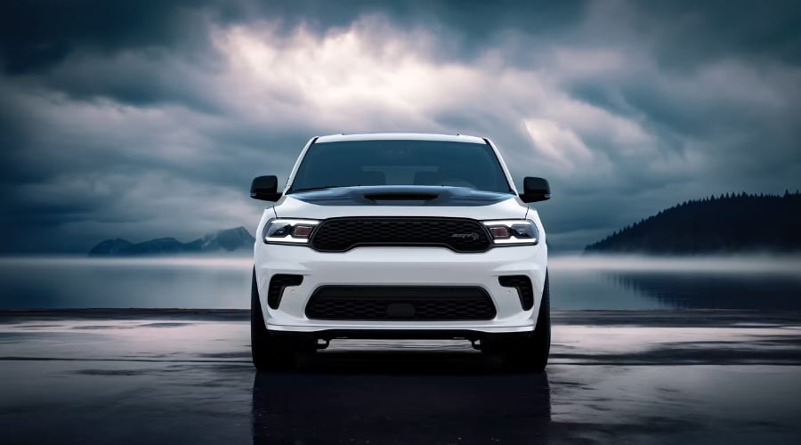 Direct front view of a white 2026 Dodge Durango with illuminated LED headlights parked on wet asphalt under dark, dramatic storm clouds, illustrating all-weather driving capability for East Brunswick NJ drivers during heavy autumn rainstorms.