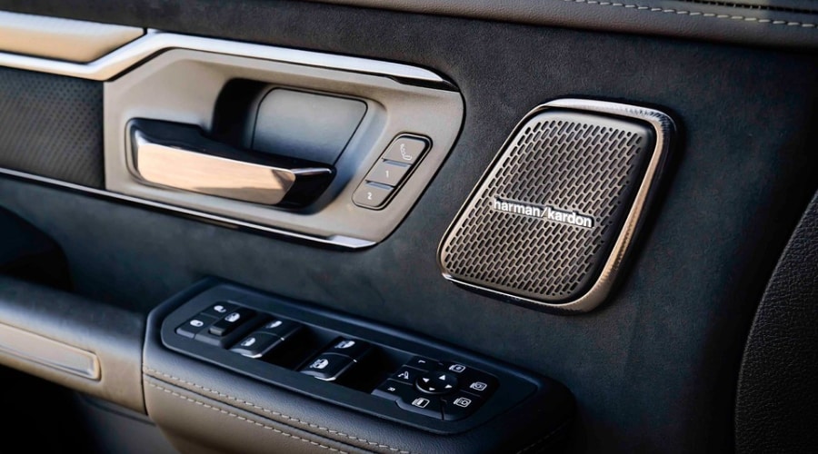 Interior door panel of a 2026 Ram 1500 featuring a Harman Kardon speaker grille, memory seat controls, and power window switches at Route 18 CJDR serving East Brunswick and Edison, NJ.
