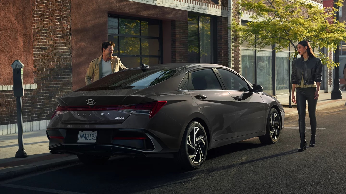 2026 Hyundai Elantra Hybrid parked on the street and a couple