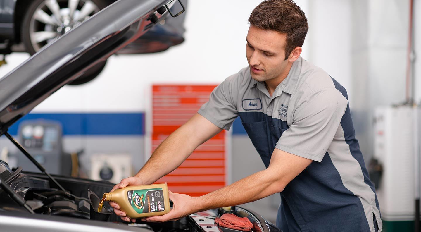 Hyundai technician pouring oil into an engine
