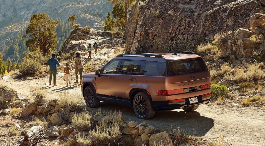 2026 Hyundai Santa Fe parked on the side of a rocky hill with family nearby.