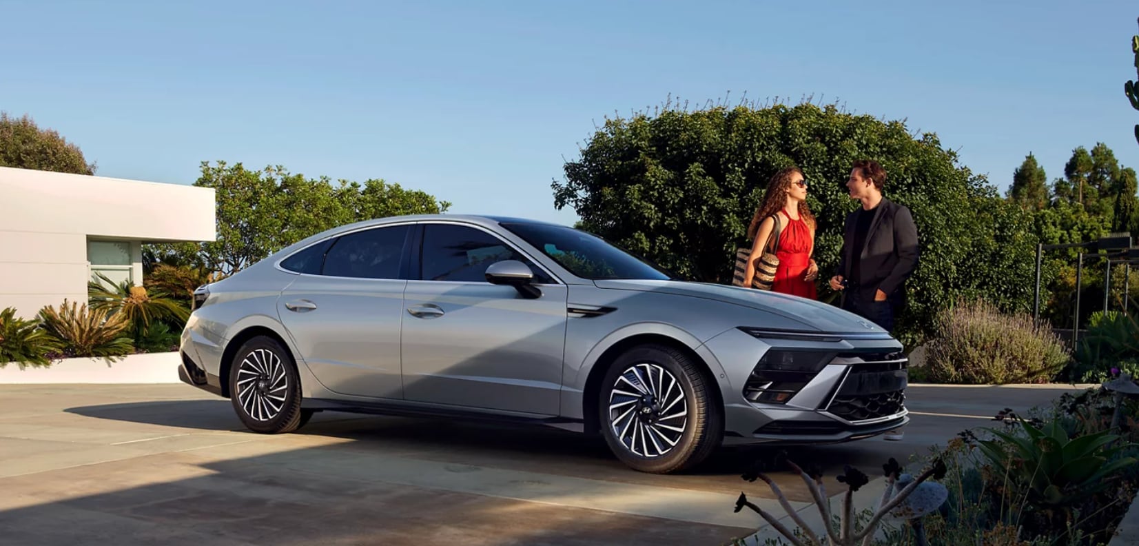 2026 Hyundai Sonata Hybrid parked in driveway with couple getting in.