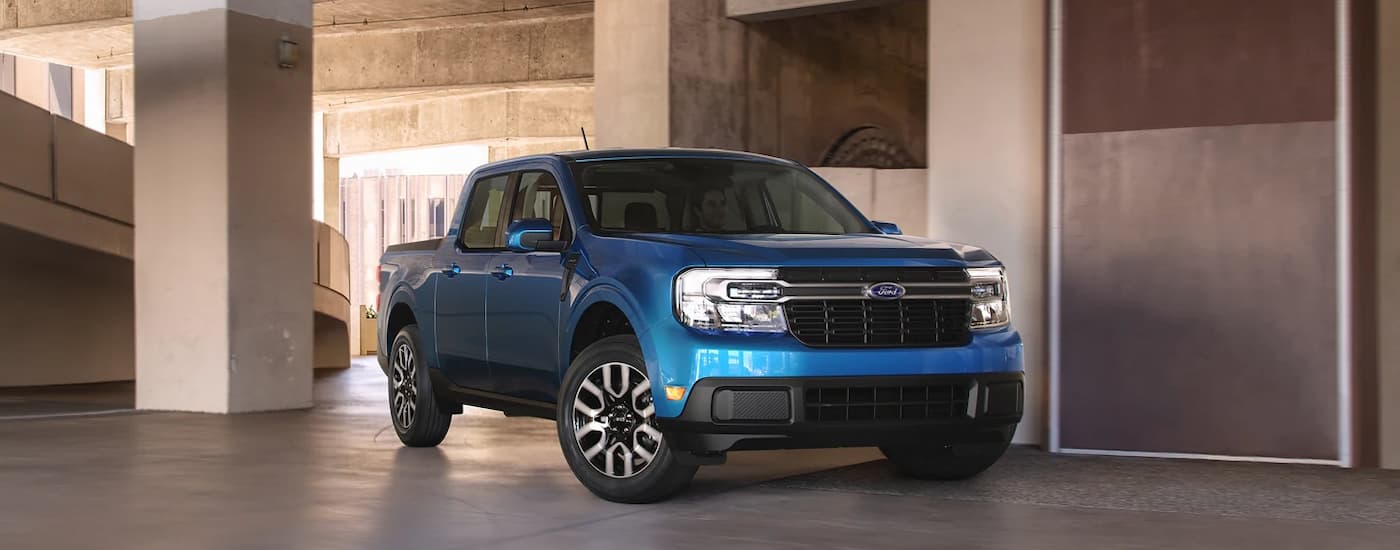 A blue 2022 Ford Maverick is shown driving through a parking garage.