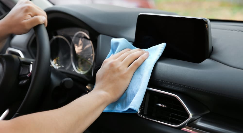A close up shows someone cleaning their dashboard being going to 'sell my car.'