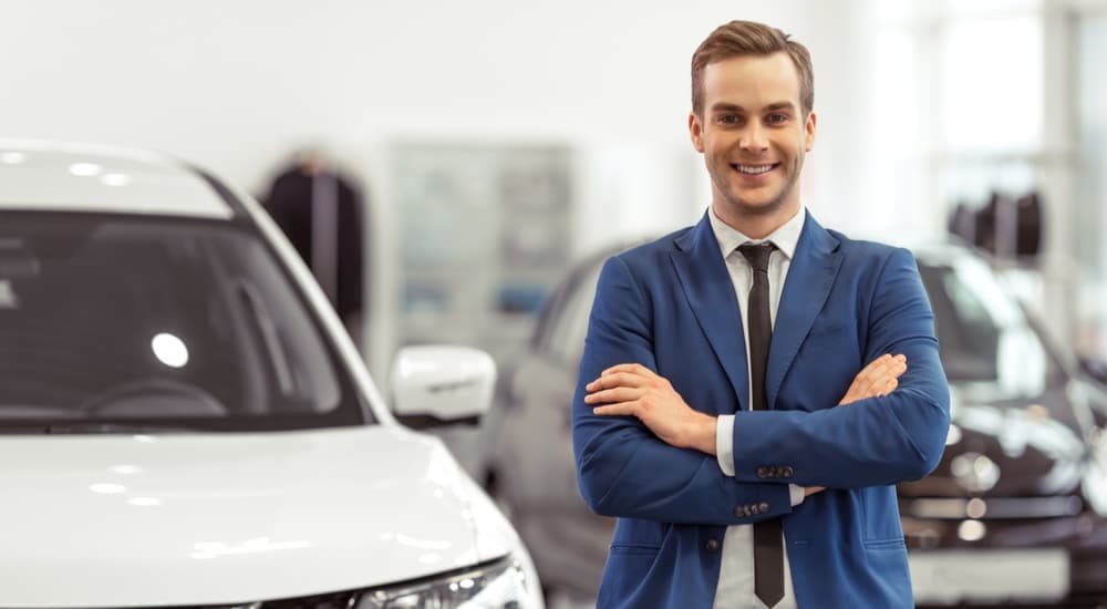A salesman is shown standing in a dealership after looking at a car's trade-in value.