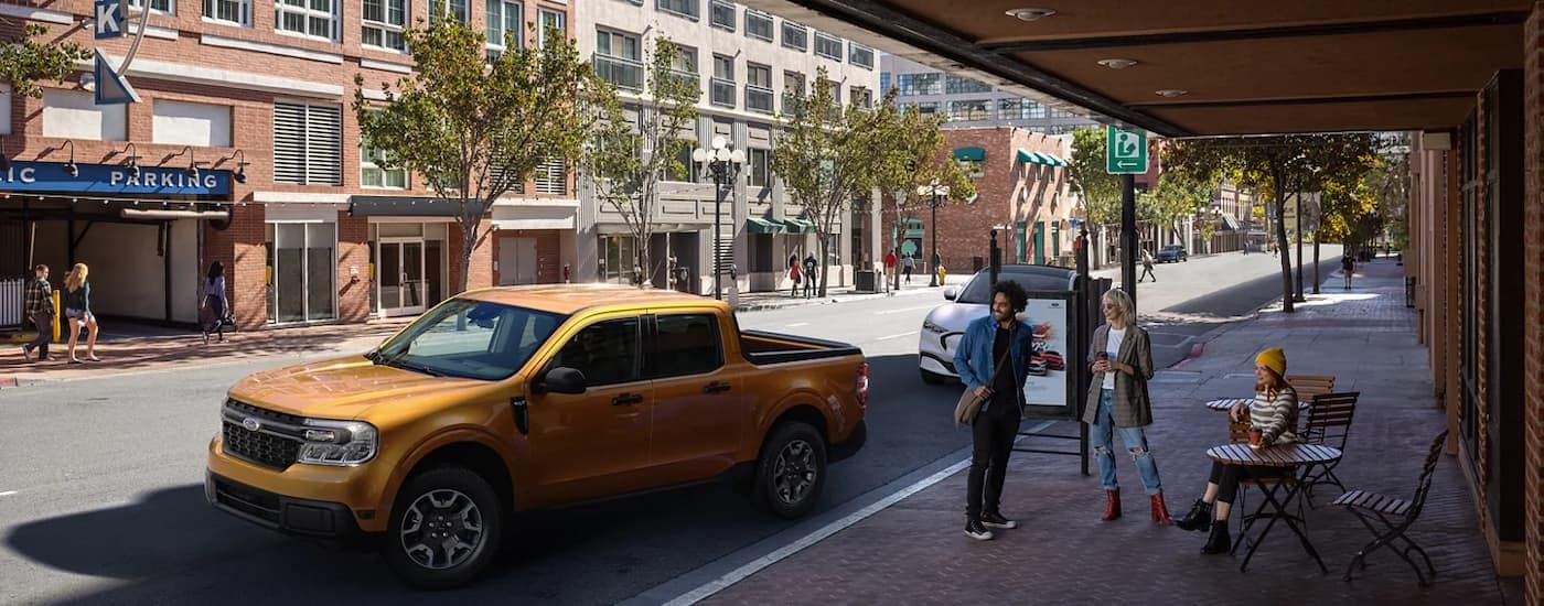 A yellow 2023 Ford Maverick is shown from the side on a city street.