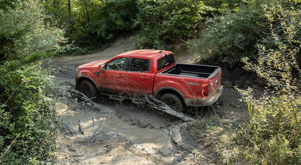 A red 2021 Ford Ranger Tremor Lariat is shown driving through mud after leaving a New Paltz Ford dealer.