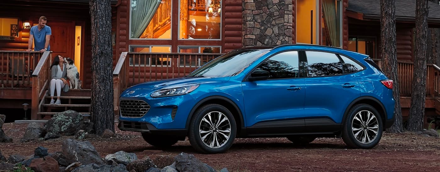A blue 2021 Ford Escape is shown from the side parked near a cabin.